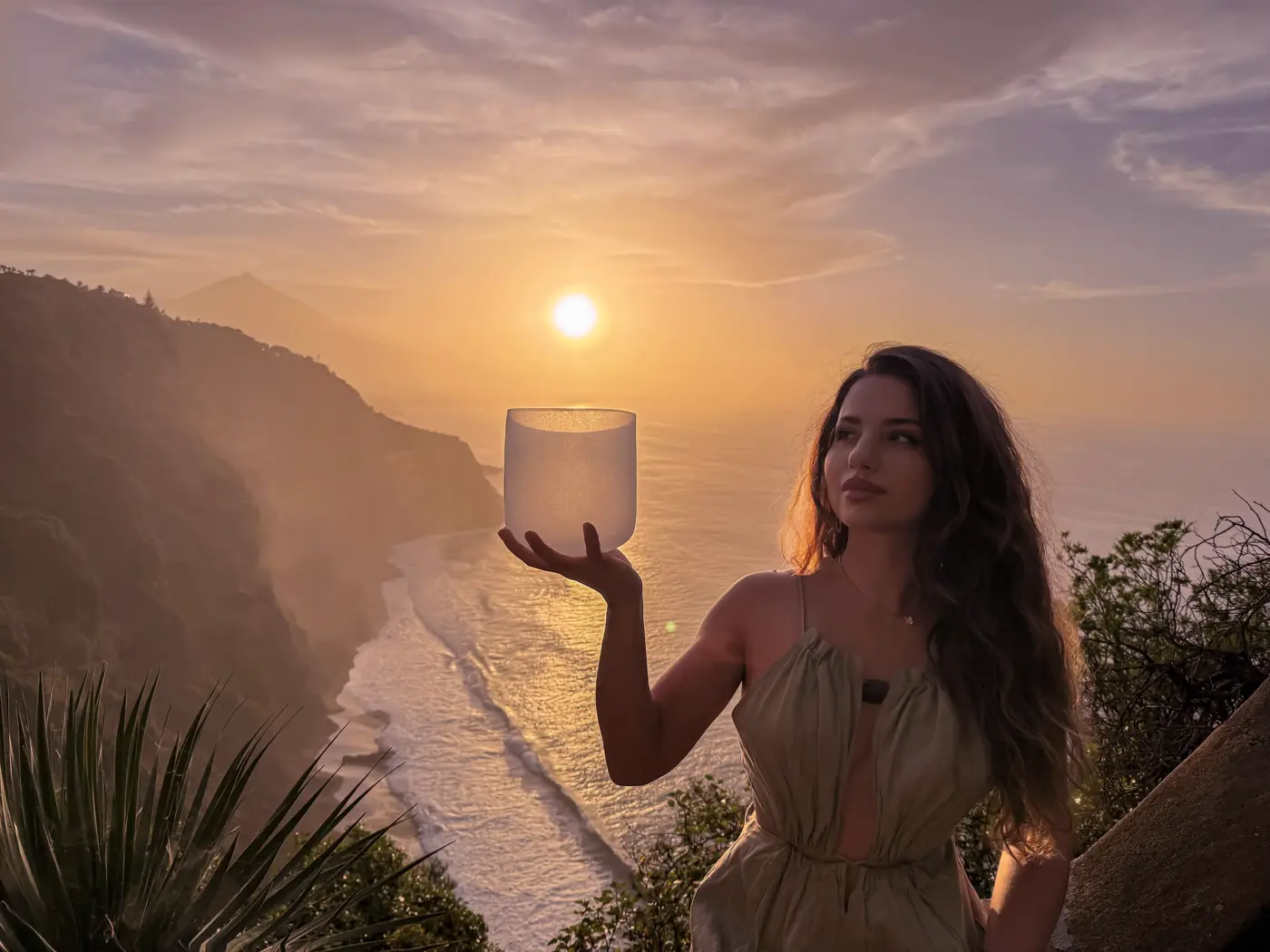Xenia Costinar ținând un bol de cristal la apus, deasupra oceanului